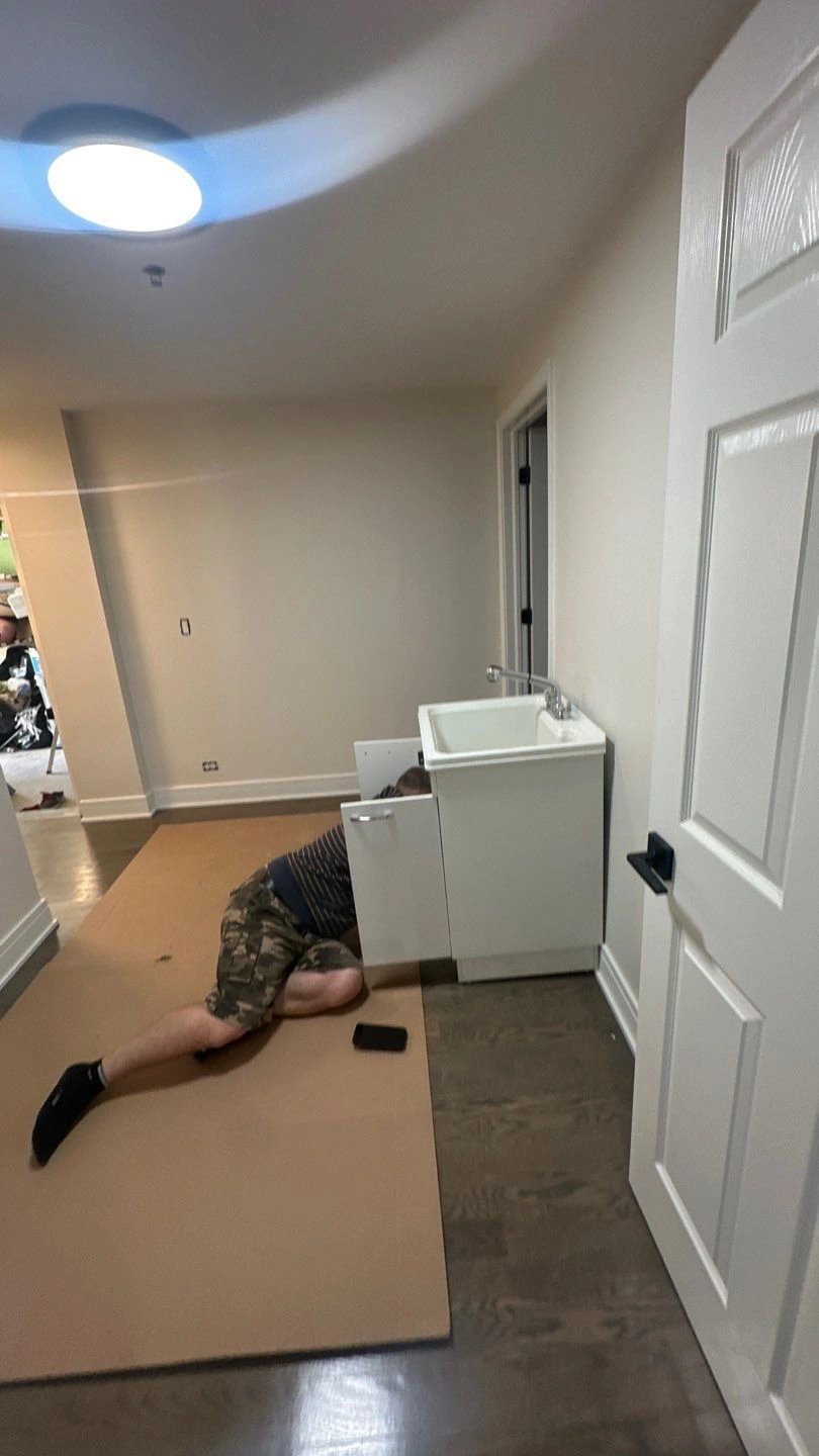 Person fixing plumbing under sink in a kitchen