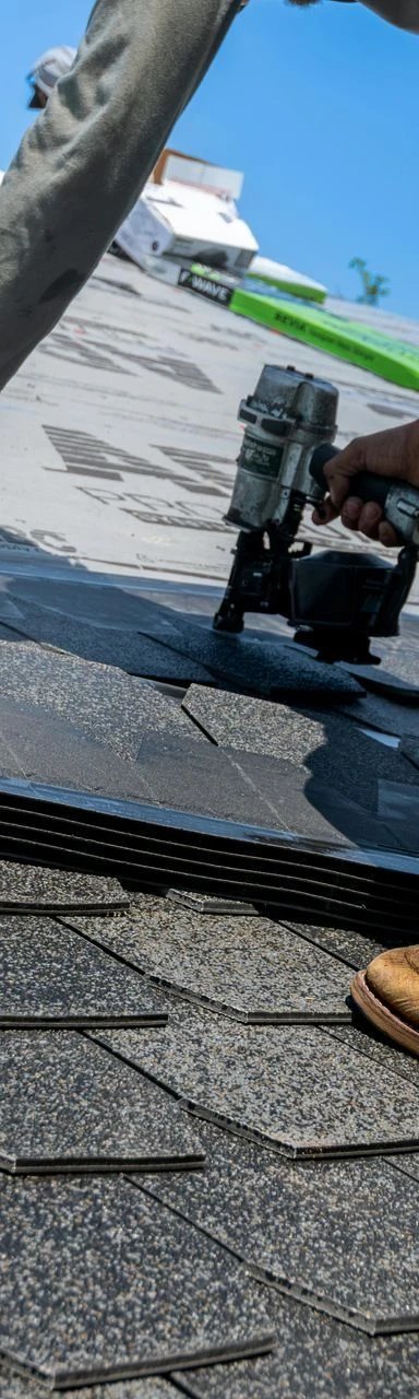A worker installing shingles on a roof.