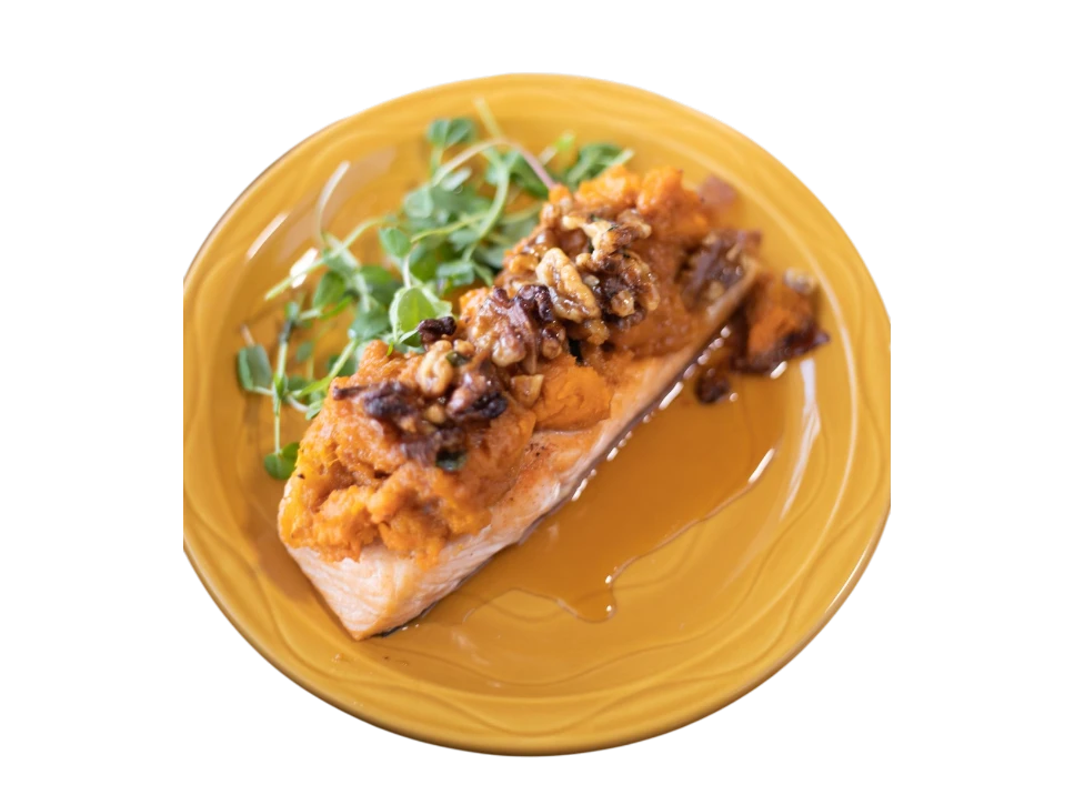 Plated salmon with a nut topping and greens.