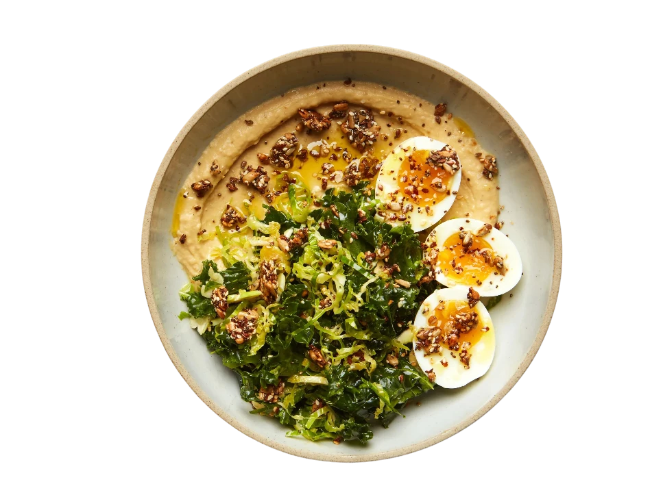 Healthy meal with greens, eggs, and hummus on a plate