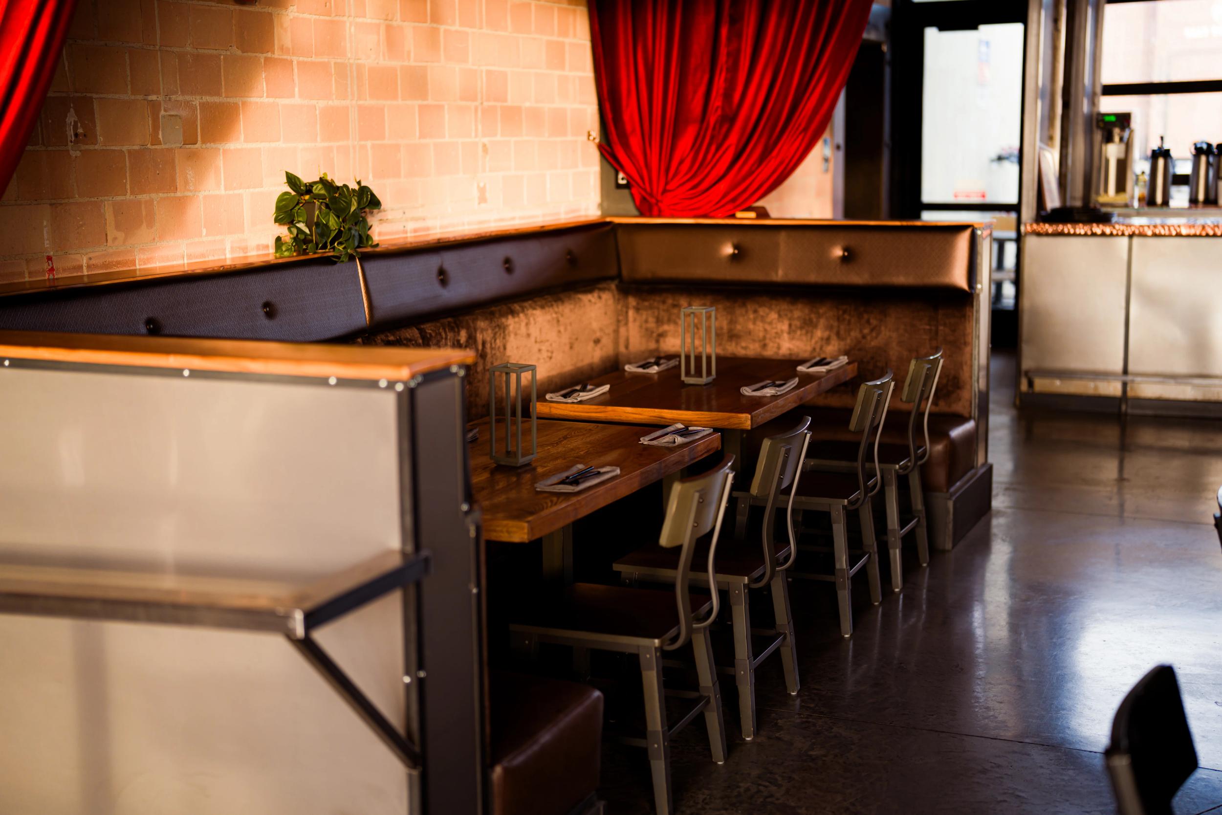 Interior of a cozy restaurant with wooden tables and elegant red drapery.