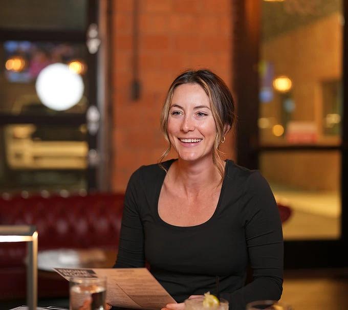 Woman smiling while reading a menu in a restaurant