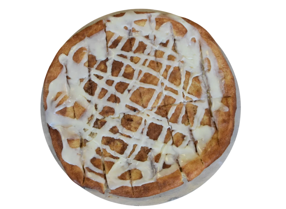 Cinnamon roll pizza topped with icing, cut into slices.