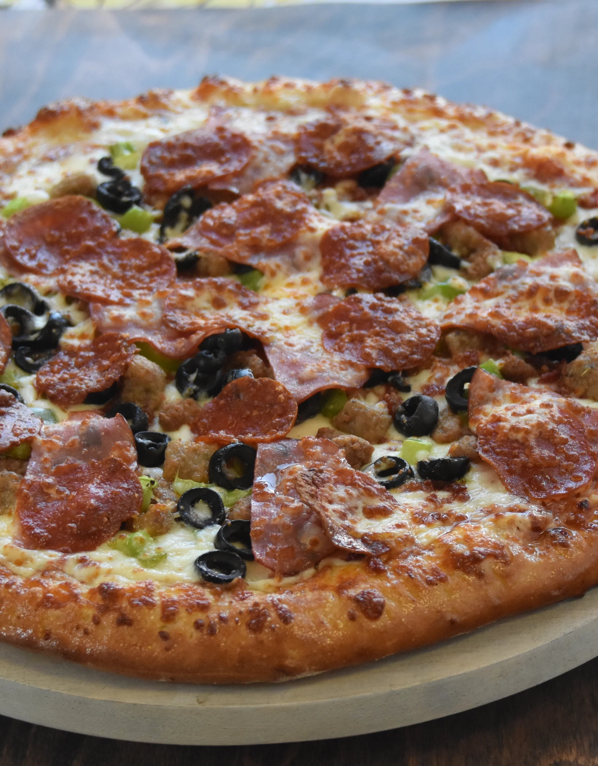 Delicious pepperoni and olive pizza on a wooden table.