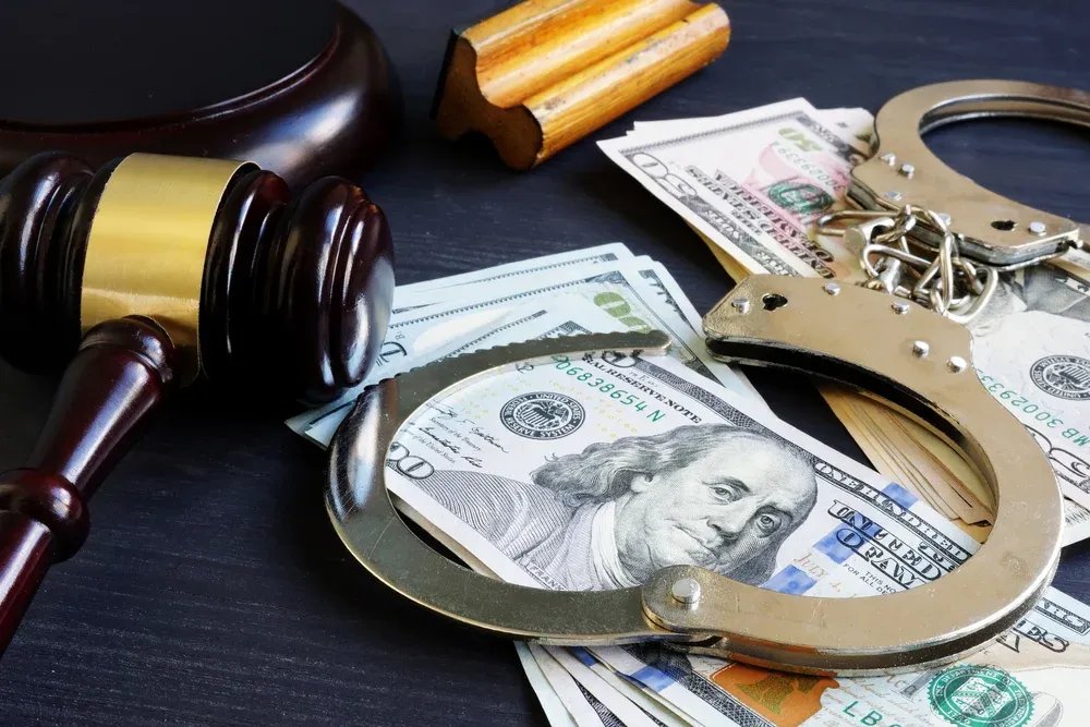 Gavel, handcuffs, and money on a table
