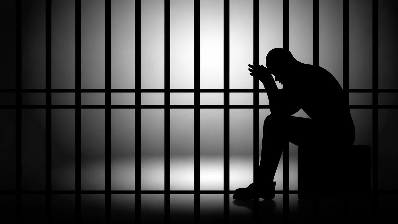Silhouette of a seated figure in a jail cell, conveying despair