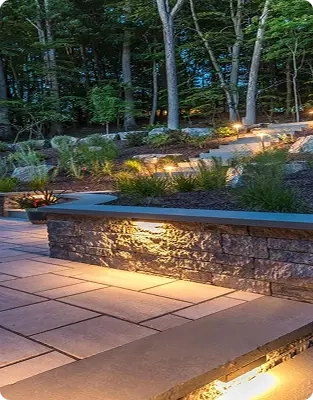 Beautifully lit stone patio in a lush garden setting at night