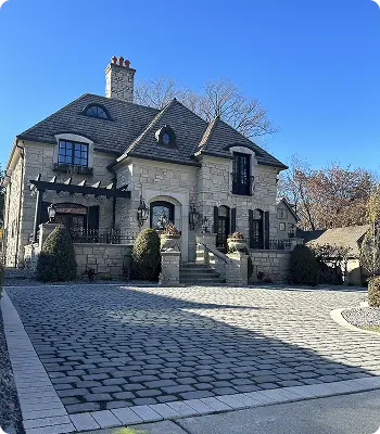 Elegant stone house with landscaped yard in clear sky