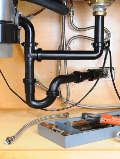 Under-sink plumbing with tools and pipes