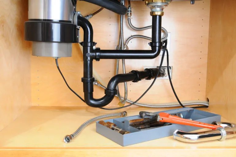 Under-sink plumbing with tools and pipes