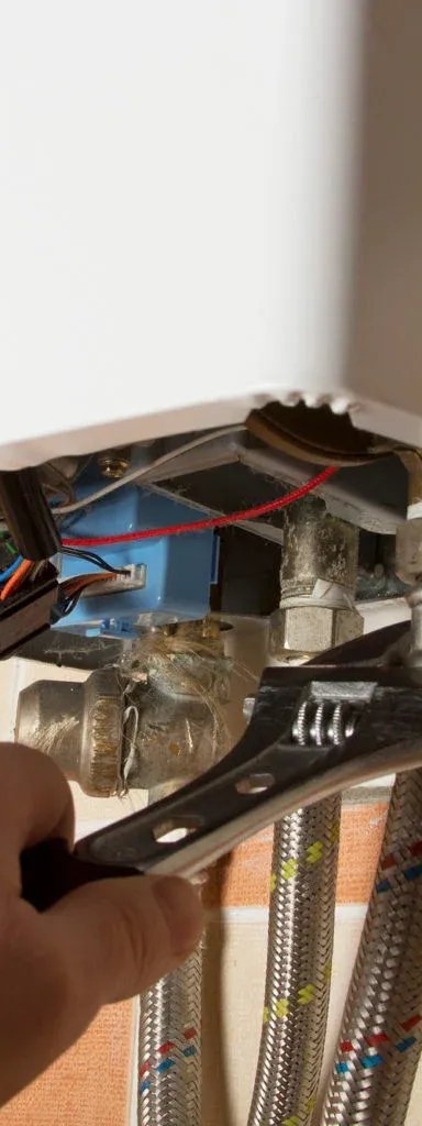 Hand using a wrench to repair a water heater.