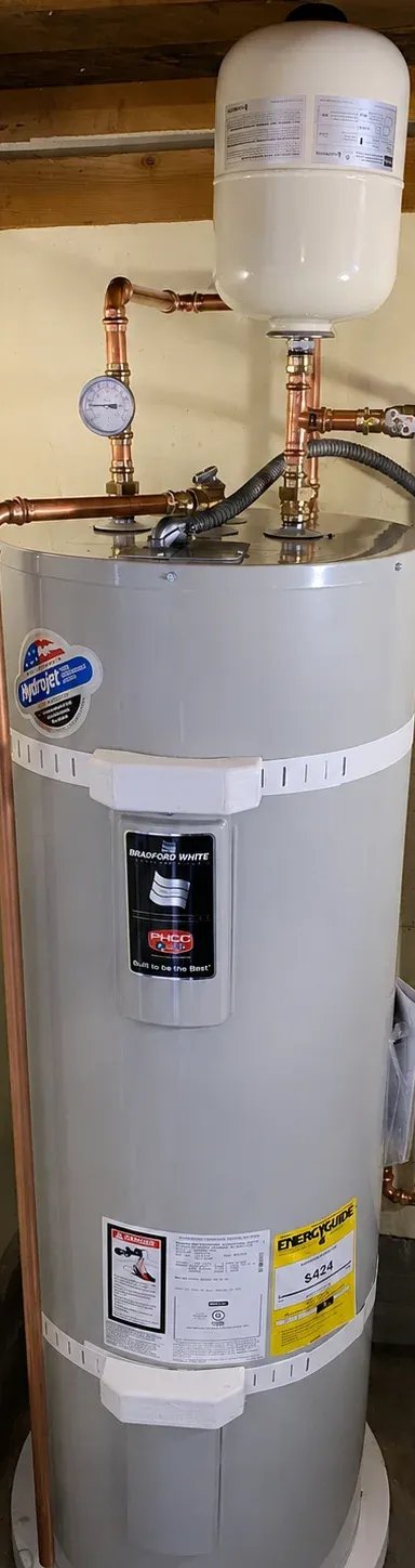 Water heater with copper pipes and gauge in utility room.
