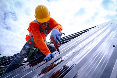 Construction worker installing metal roofing
