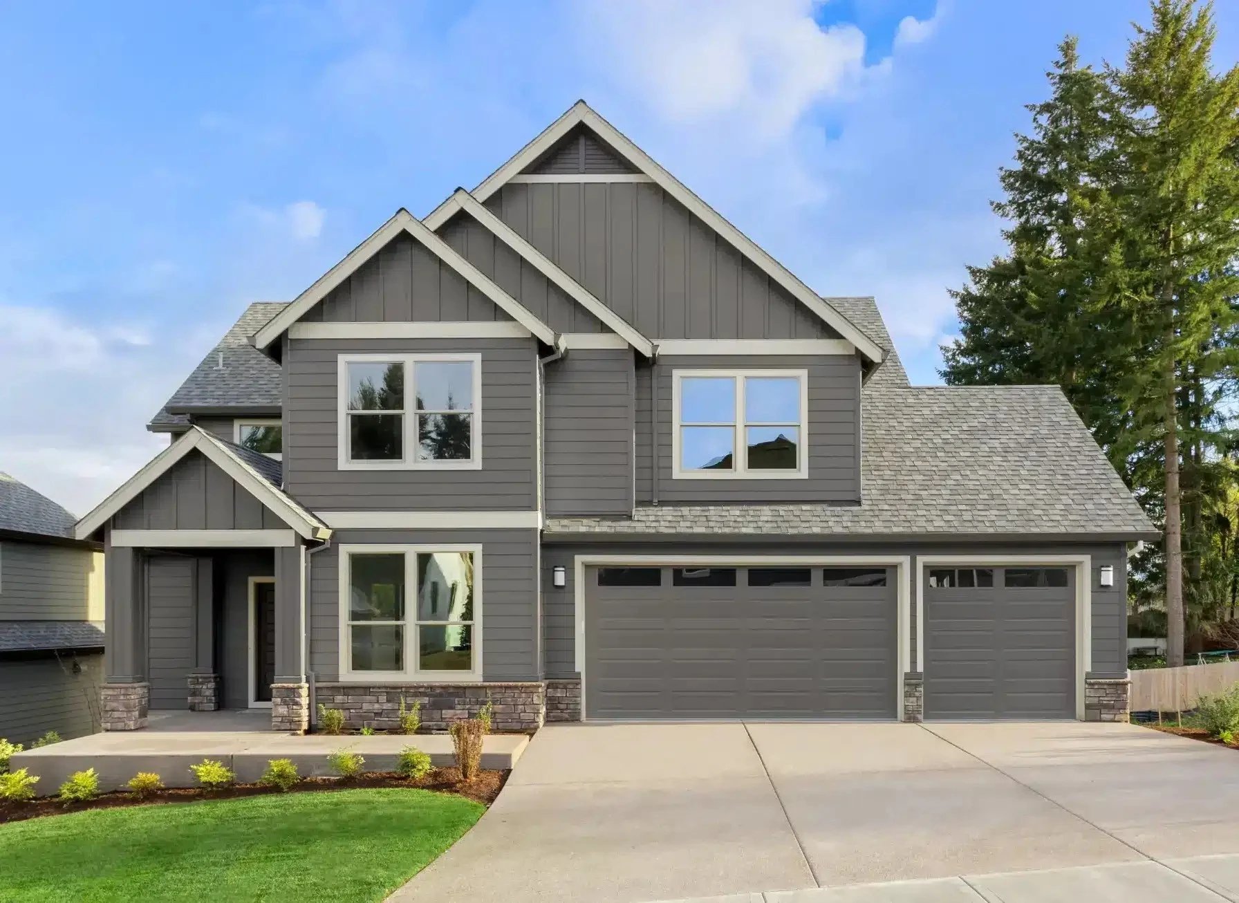 Modern gray house with large windows and driveway.