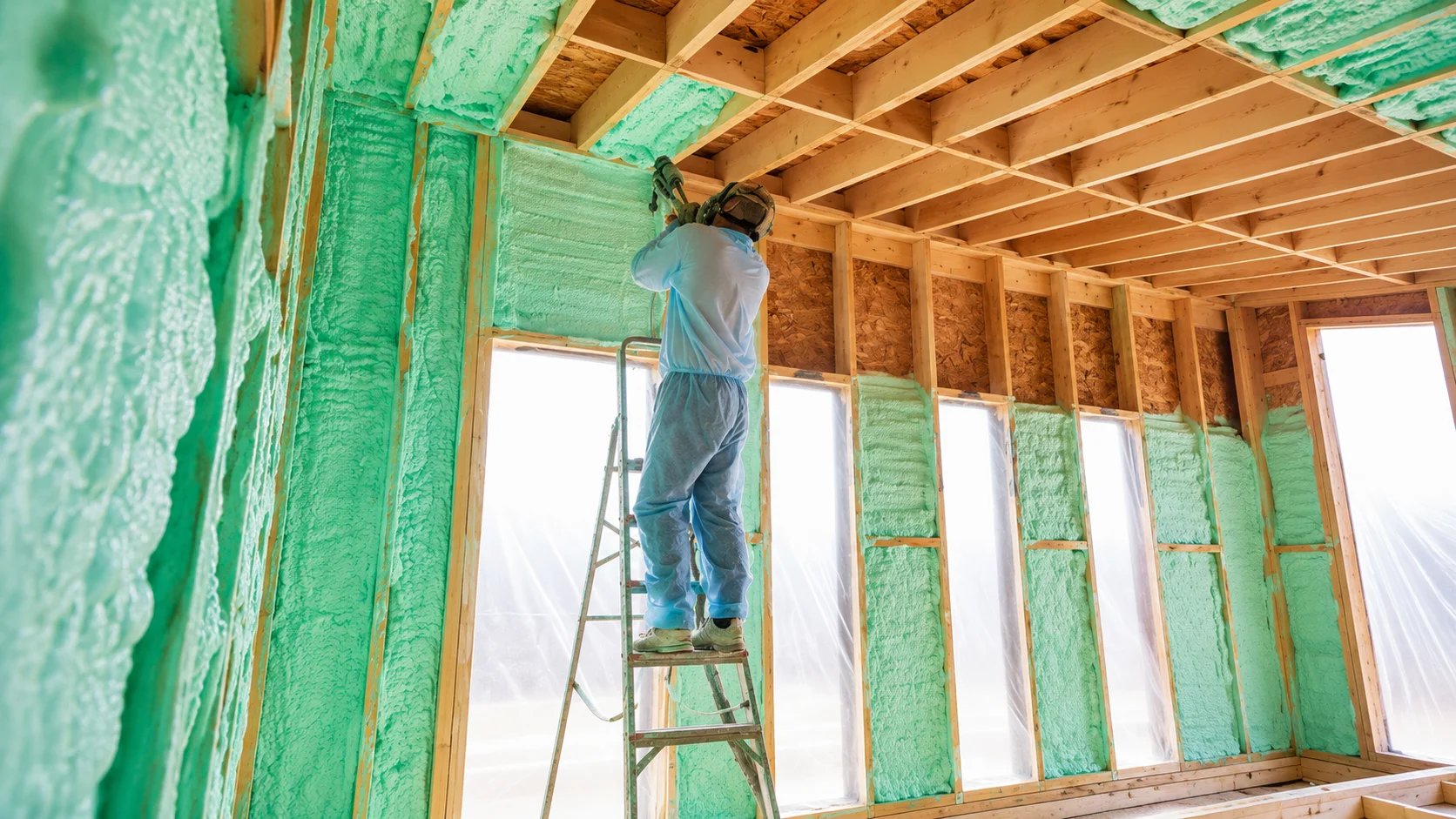 Worker installing insulation in a house
