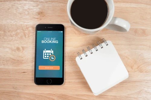 Mobile phone displaying online booking app with a coffee cup and notepad