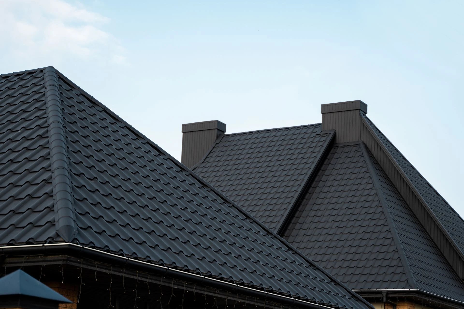 Black metal roofs reflecting sunlight under blue sky