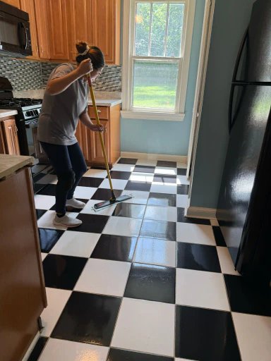 Person mopping a black-and-white checkered floor in a kitchen