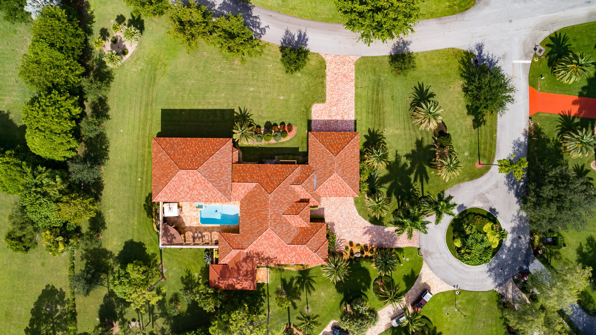 Aerial view of a luxurious villa with palm trees and a pool.