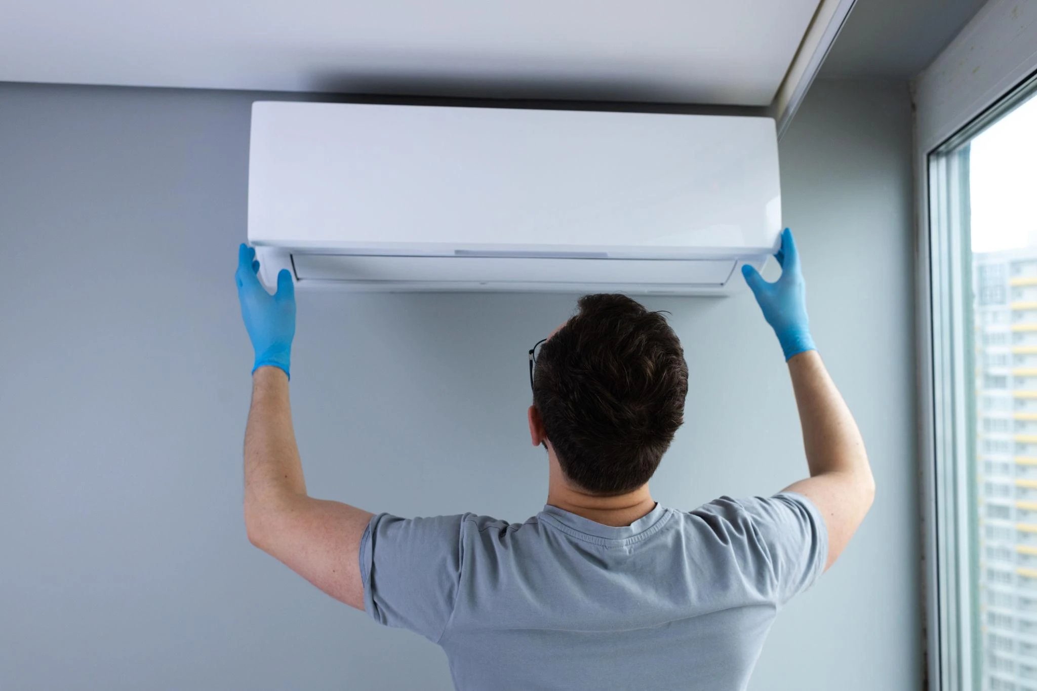 Technician installing air conditioning unit on wall