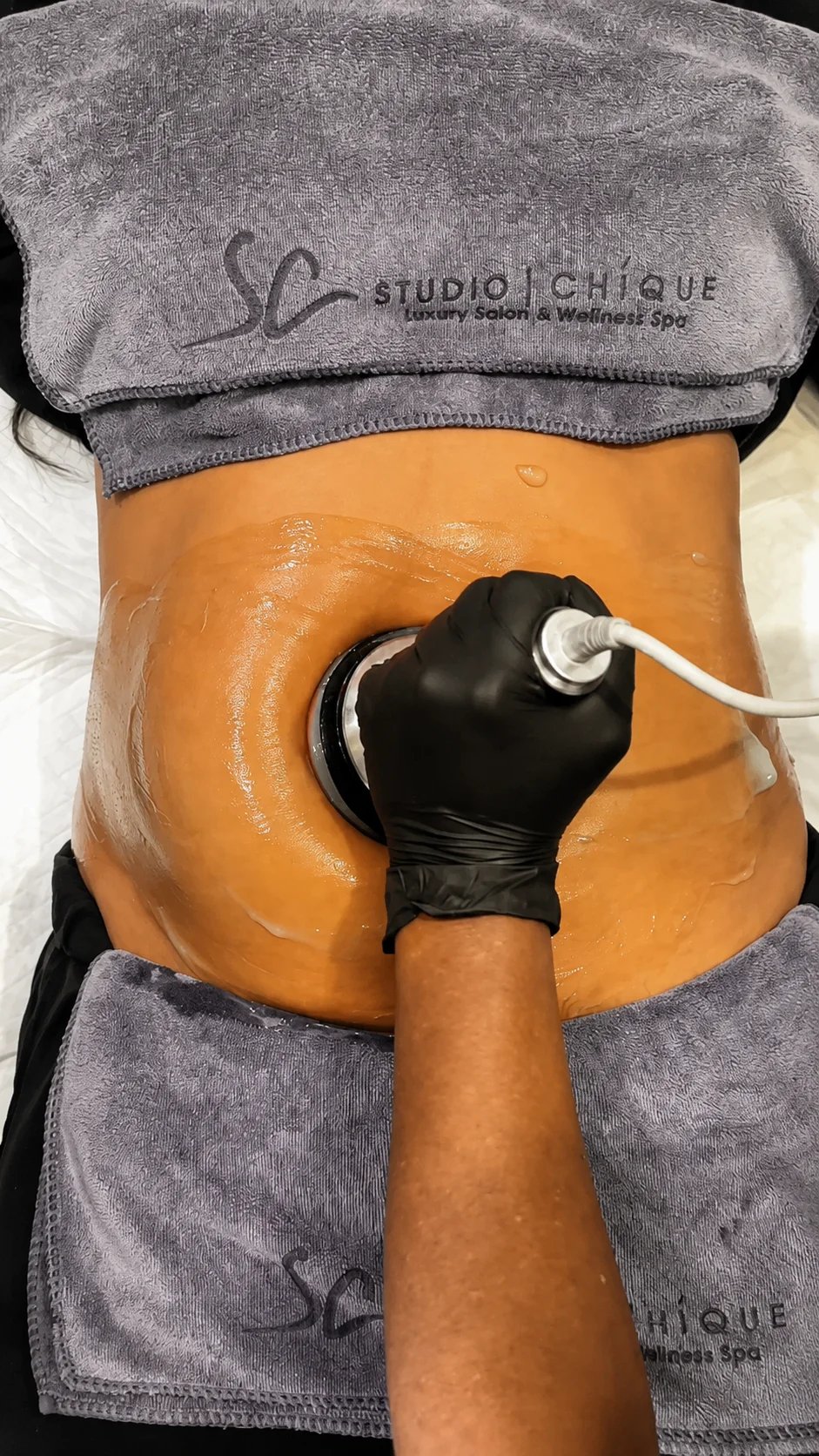 An aesthetic treatment device being used on a person's abdomen at a spa.