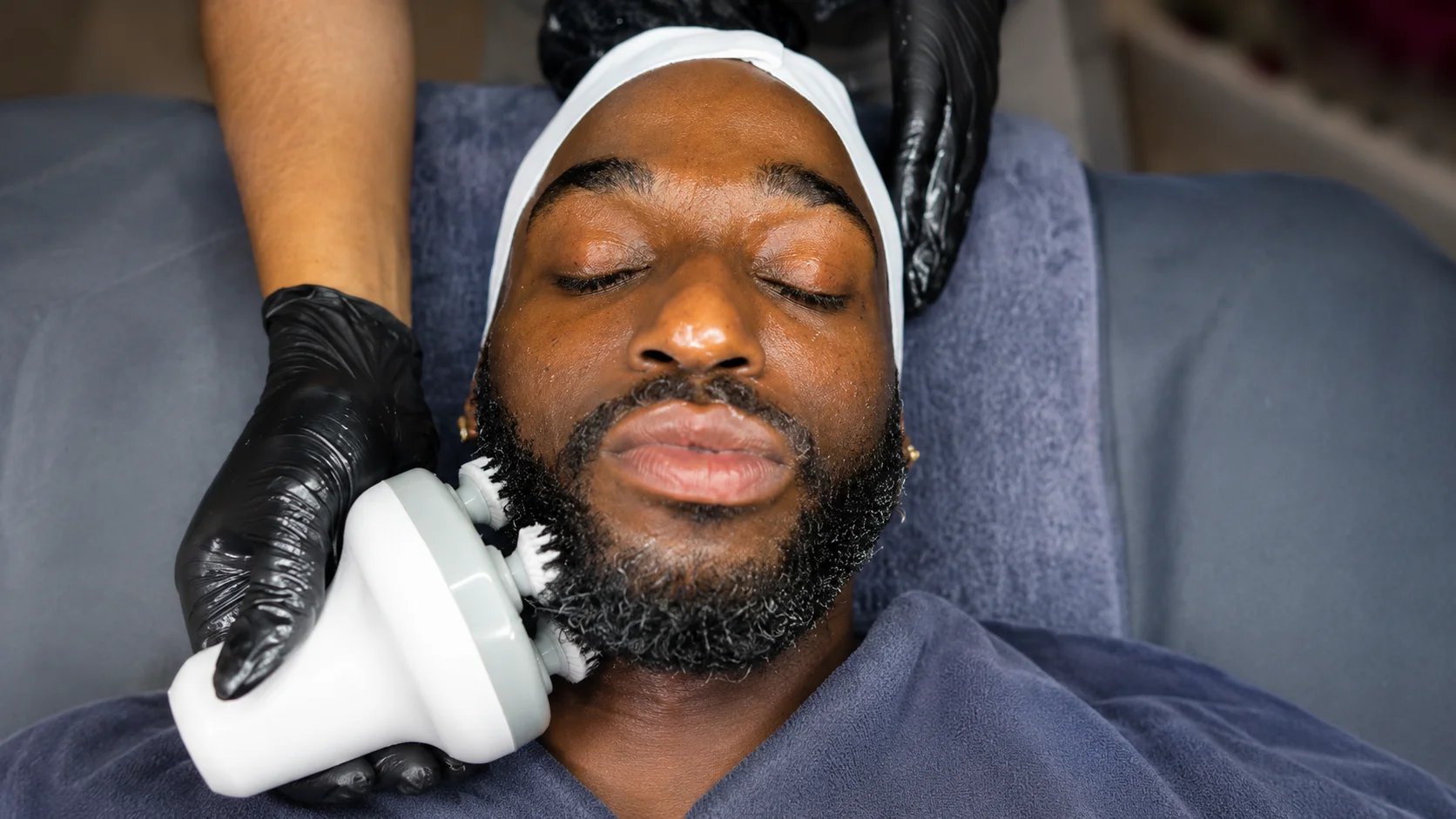 Man receiving facial treatment with a cleansing device