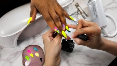 Close-up of hands receiving a colorful nail art treatment