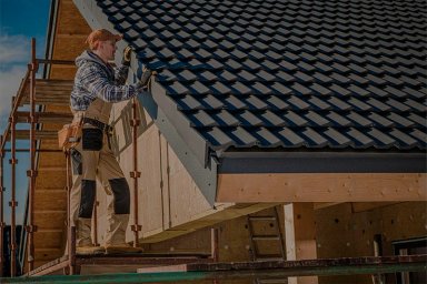 Worker installing roofing tiles on a house