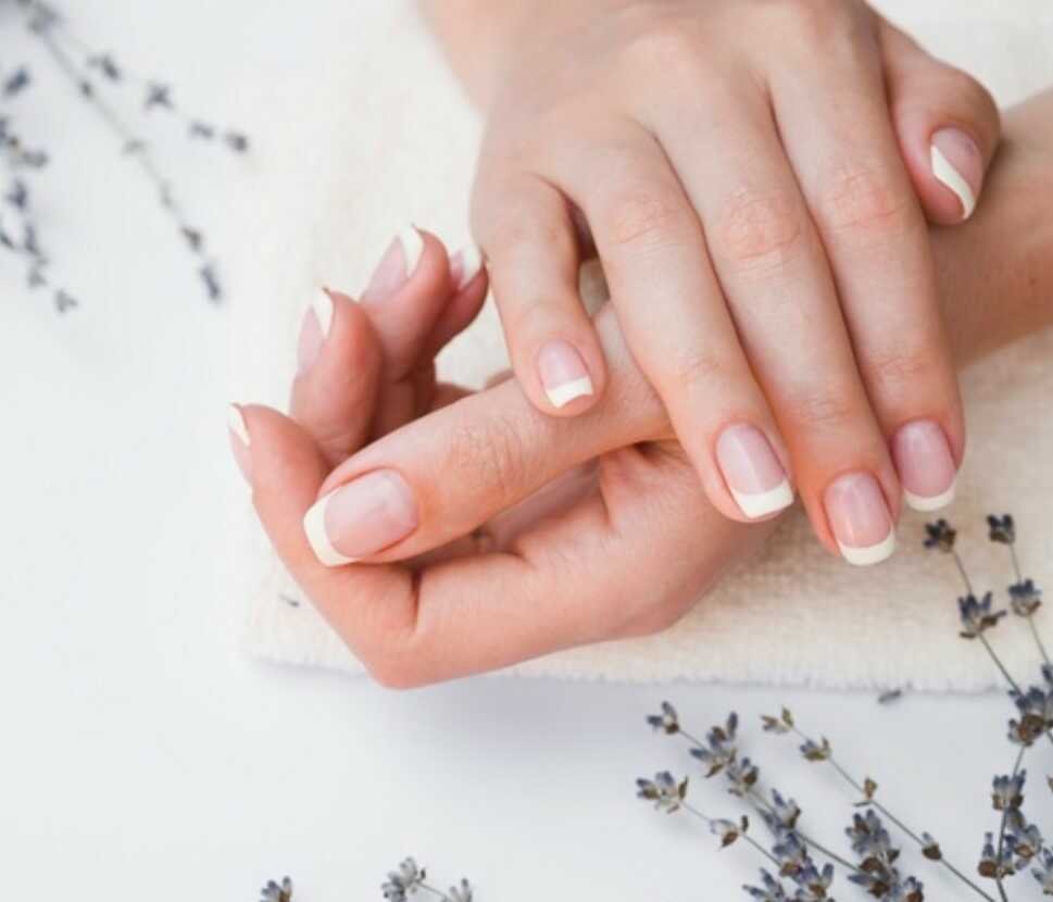 A pair of manicured hands resting on a towel with lavender sprigs.