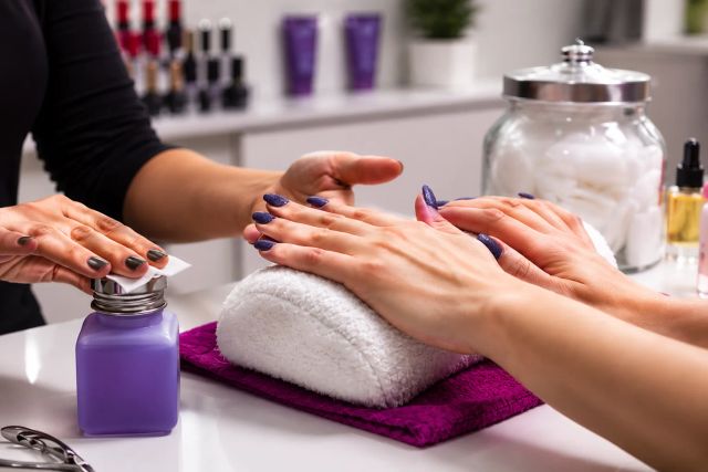 Manicure service with purple nails and products.