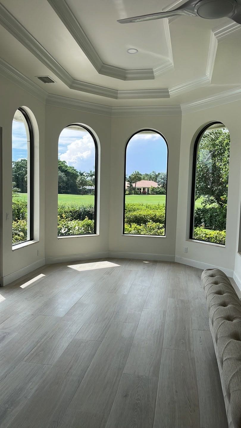 Modern interior with large arched windows overlooking a green landscape