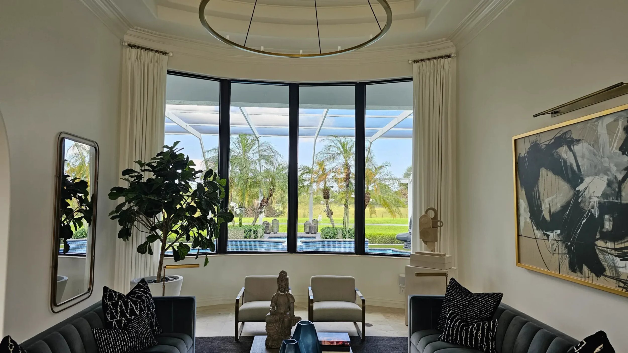 Modern living room with large windows overlooking a pool.
