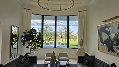 Modern living room with large windows overlooking a pool.