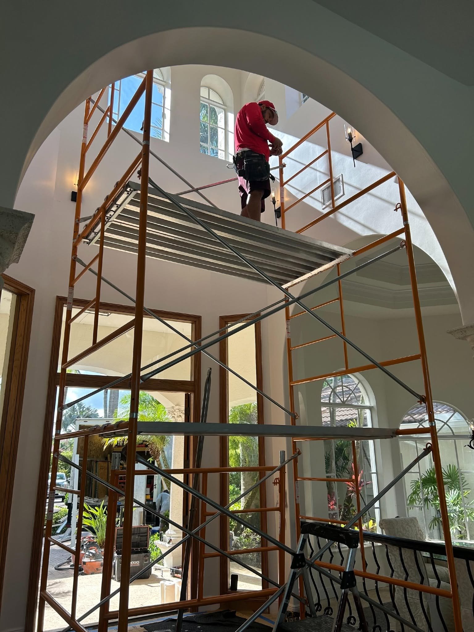 Construction worker on scaffolding in a modern interior.