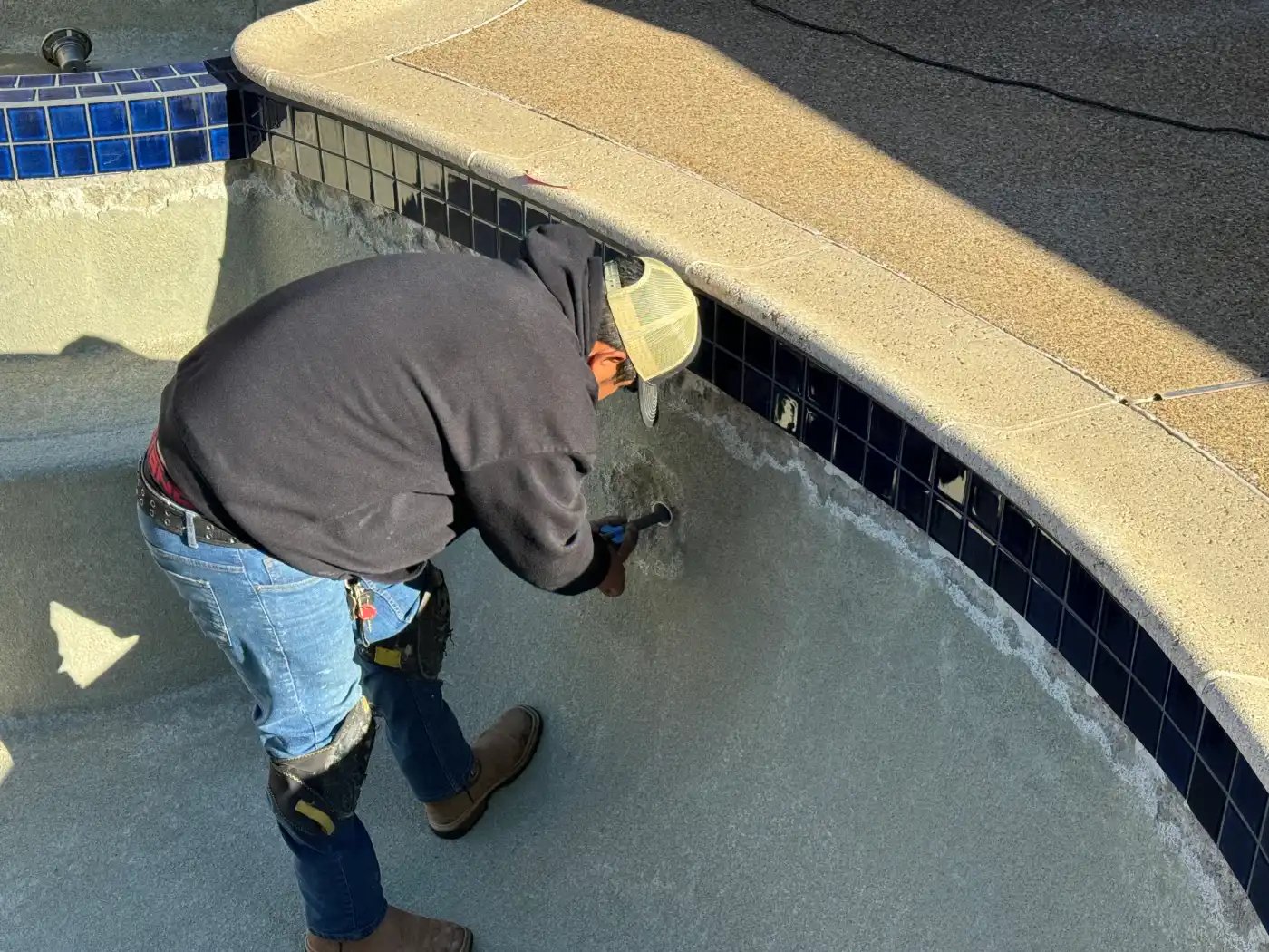 Worker performing maintenance on a pool surface