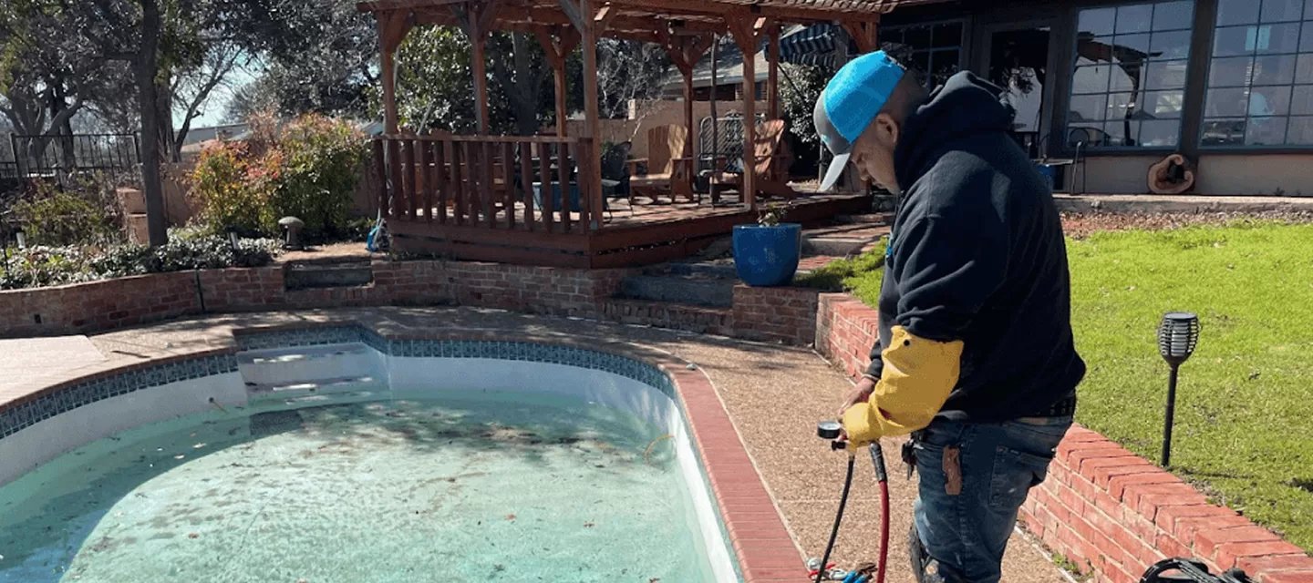 Man inspecting a swimming pool with leaves indoors