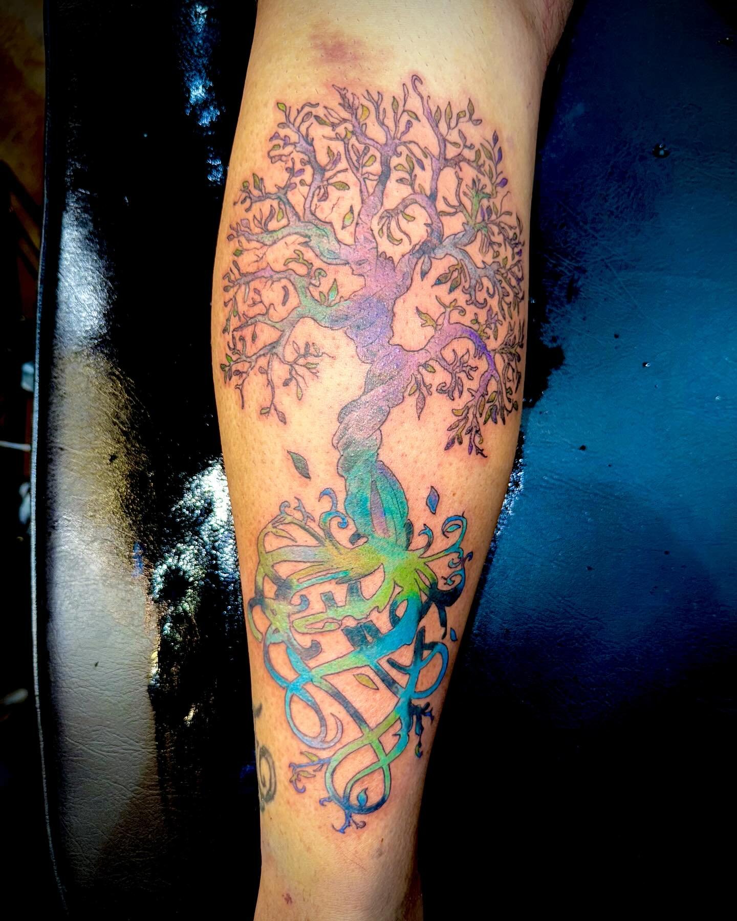 Colorful tree tattoo design on a leg