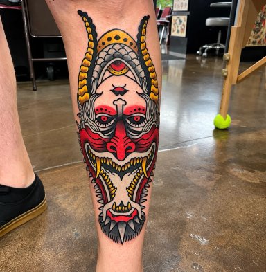 Colorful tattoo of a mask on a leg