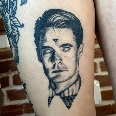 Black and white tattoo of a man's portrait on skin