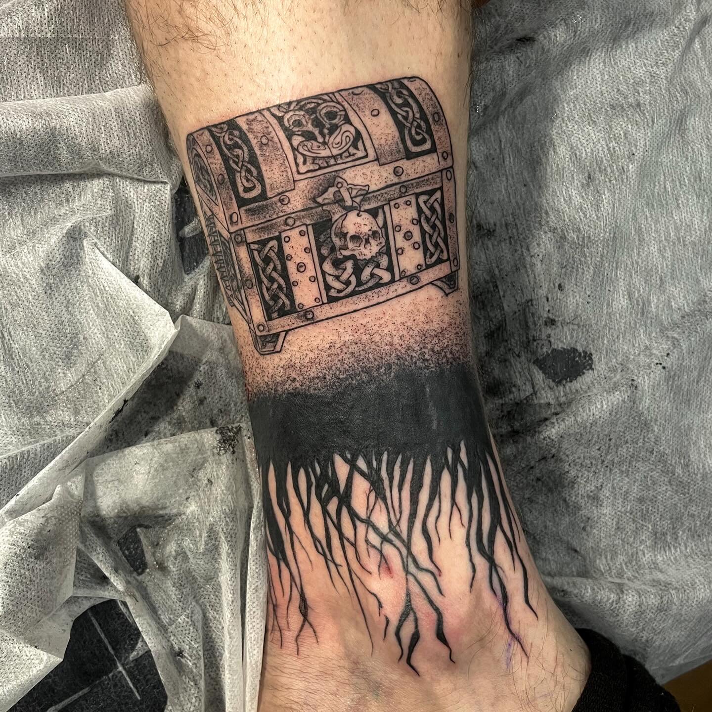 Intricate tattoo of a treasure chest with roots