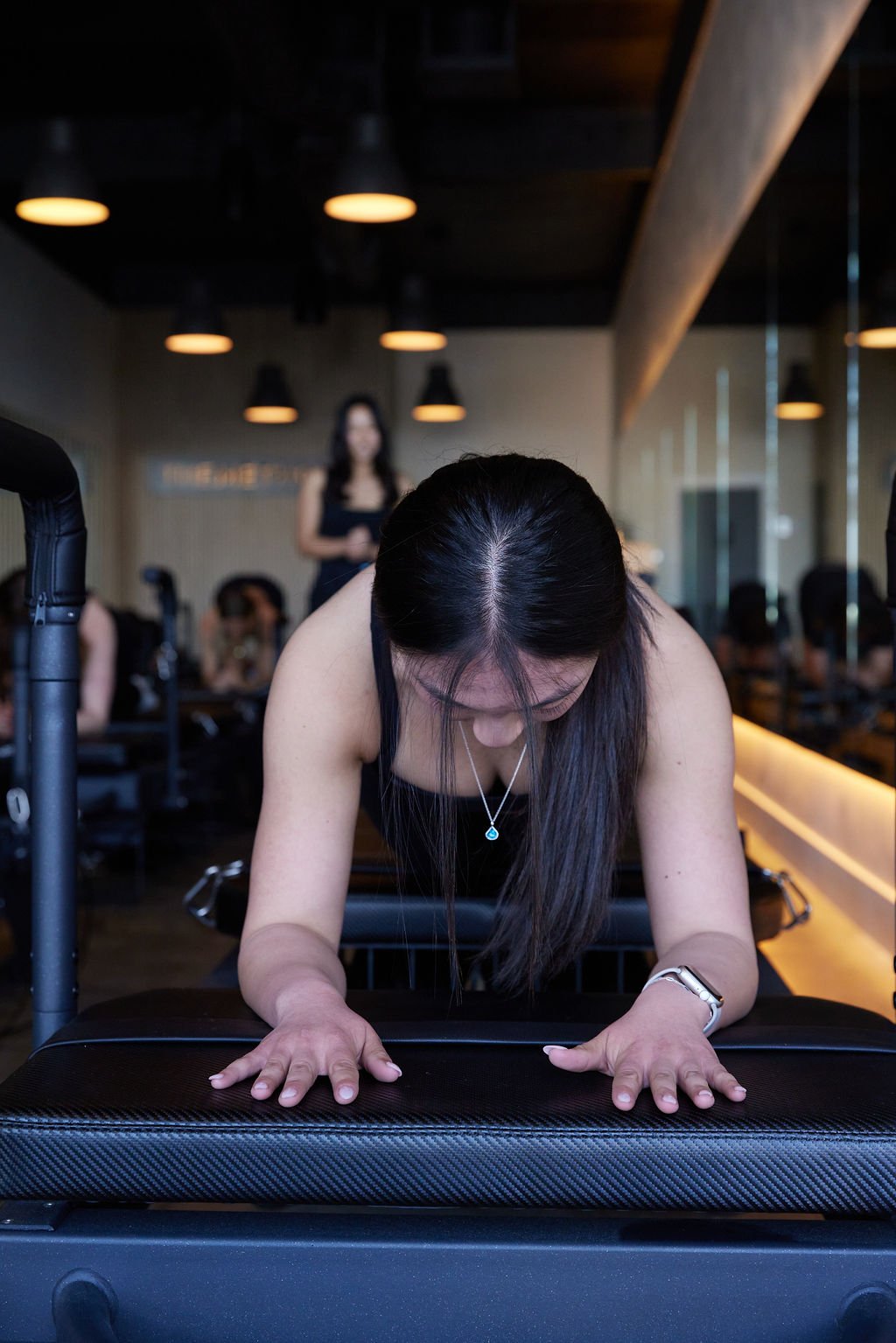 Woman engaging in a fitness workout on a reformer machine in a modern studio.