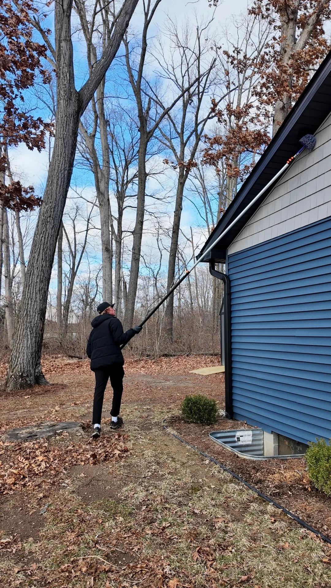 Person cleaning roof with a pole in winter setting