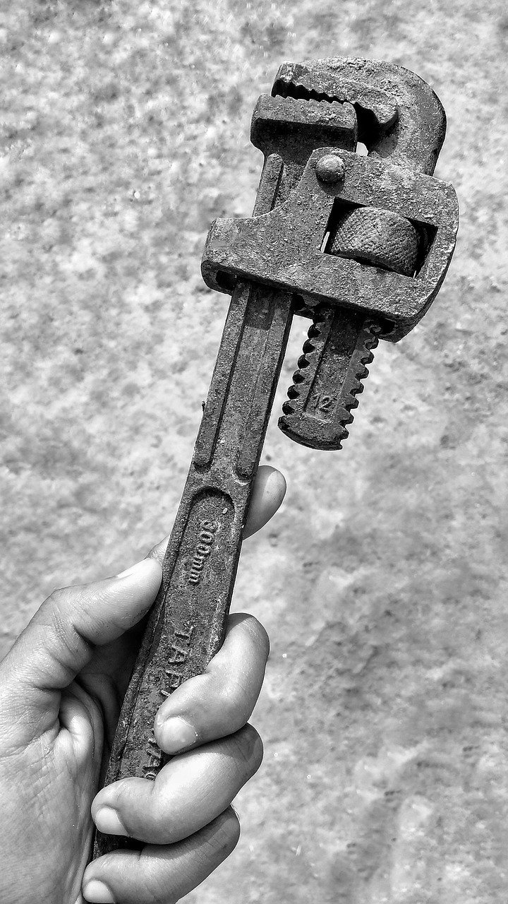 Hand holding an adjustable wrench against a textured backdrop.