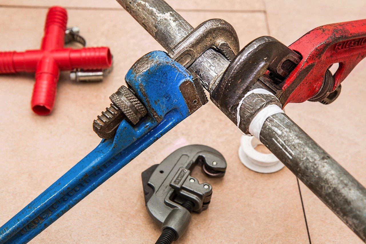 Tools used for plumbing repairs including wrenches and pipe fittings