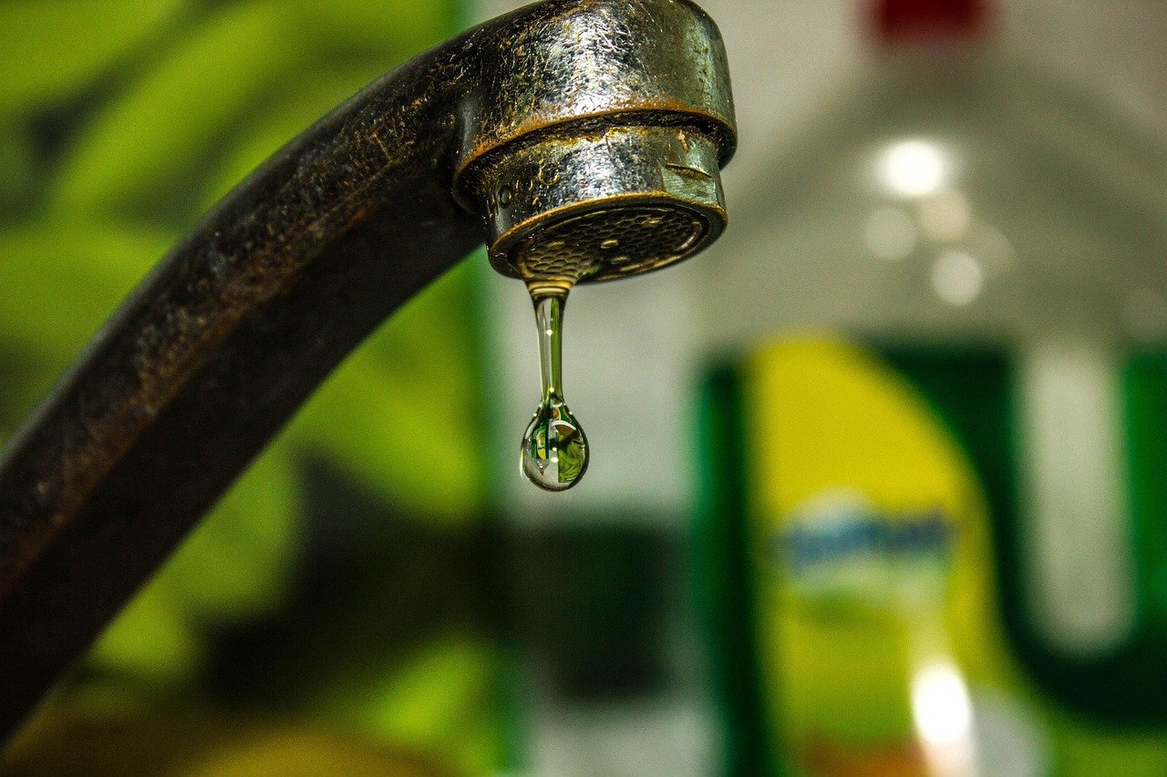 A close-up of a dripping faucet with water droplets