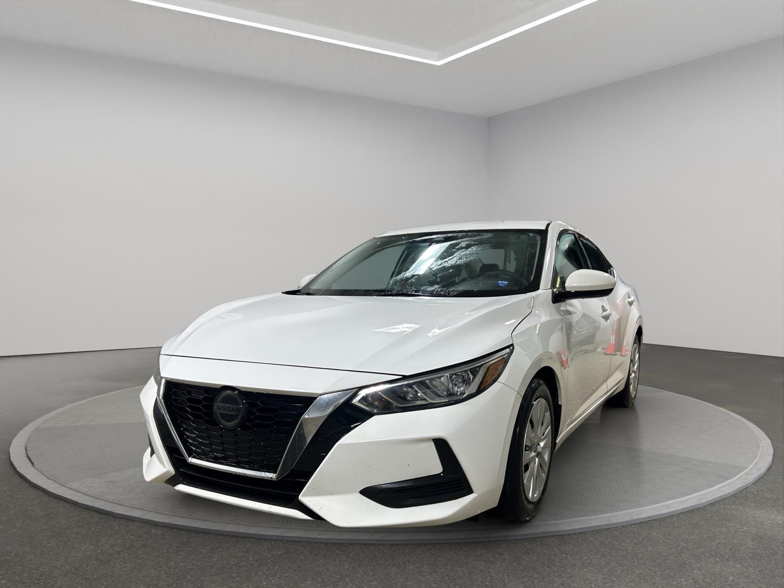 White Nissan sedan in a minimalist showroom