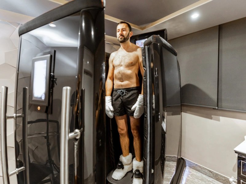 Man using cryotherapy chamber for wellness treatment.