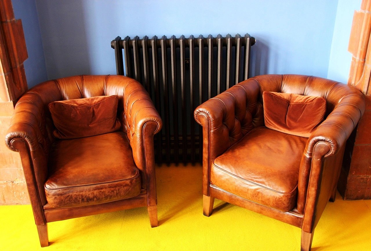 Two brown leather chairs beside a black radiator.