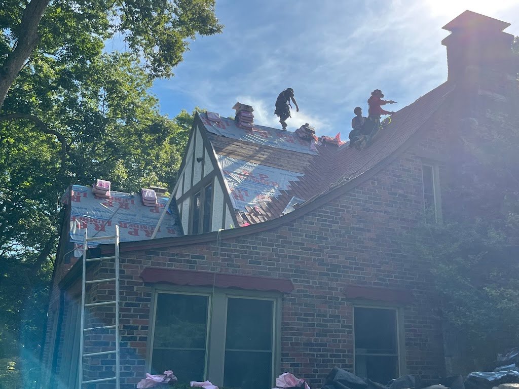 Roofing workers installing shingles on a house